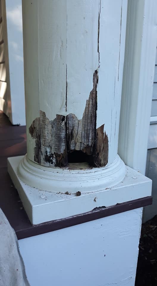 A white pole with a hole in it is sitting on a porch.
