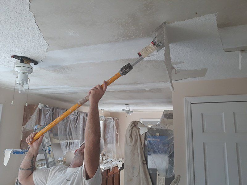 a man is painting a ceiling with a paint roller.