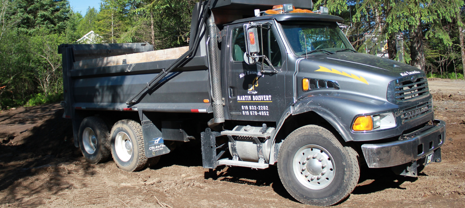 Un camion à benne basculante est garé dans un champ de terre.