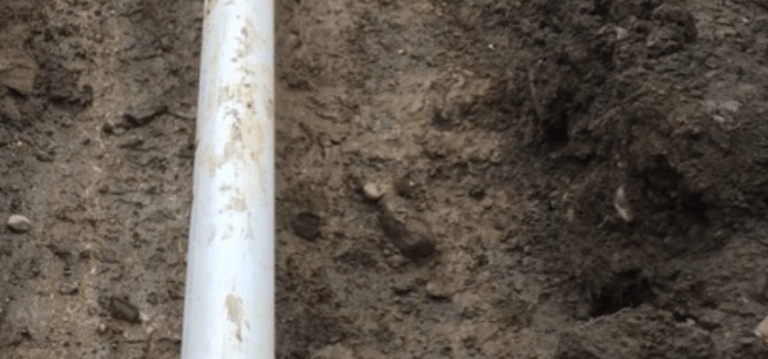 Un tuyau blanc est posé sur un tas de terre.