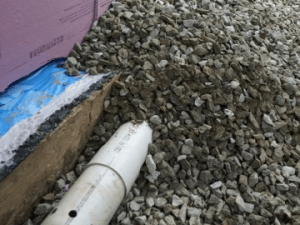 Un tuyau blanc est posé sur un tas de gravier.