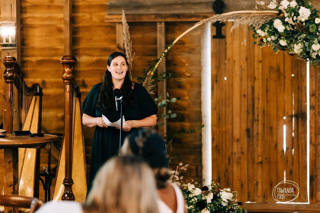 A woman is standing in front of a microphone giving a speech at a wedding.