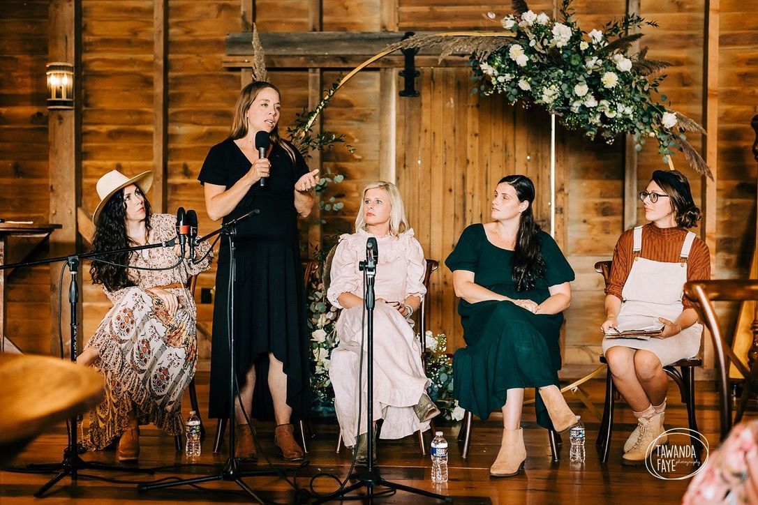 A group of women are sitting in chairs and standing in front of a microphone.
