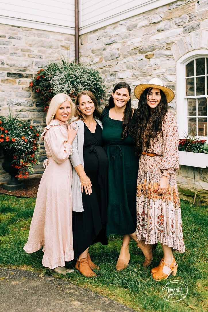 A group of women are posing for a picture in front of a stone building.