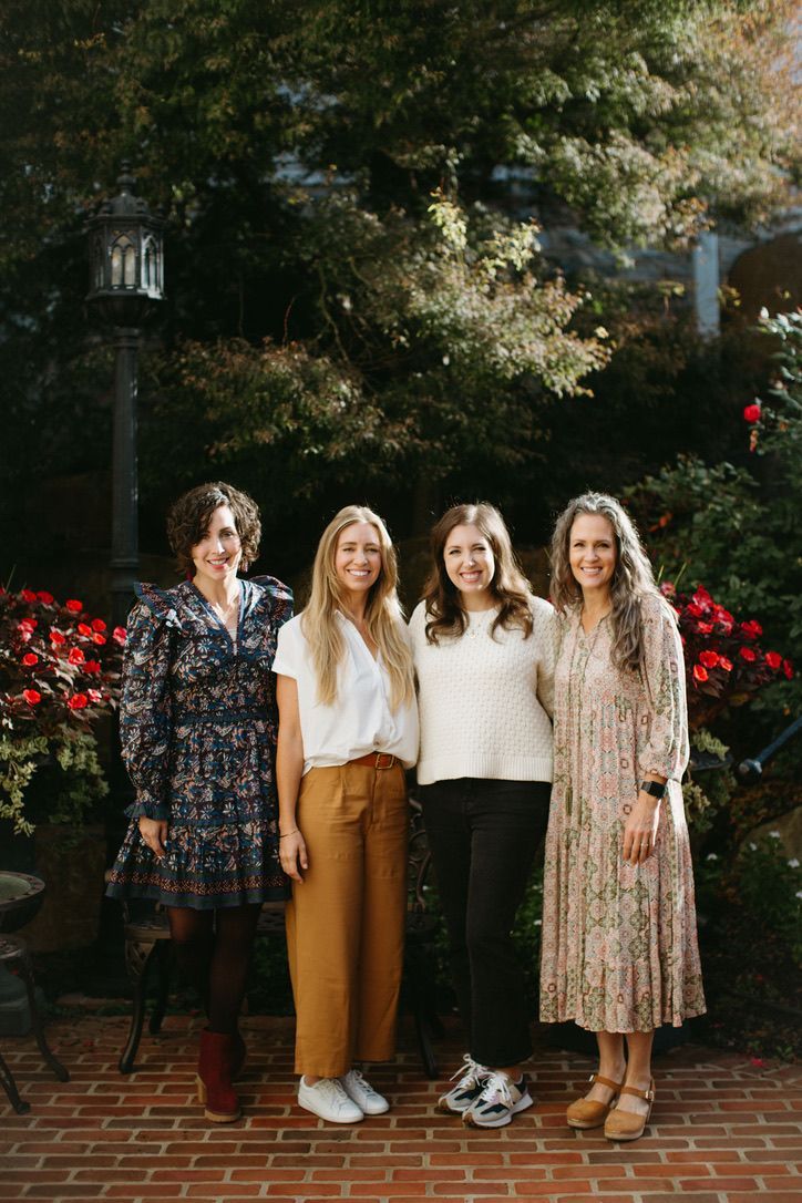 A group of women are standing next to each other on a brick sidewalk.