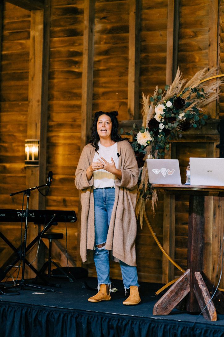 A woman is standing on a stage in front of a wooden wall.