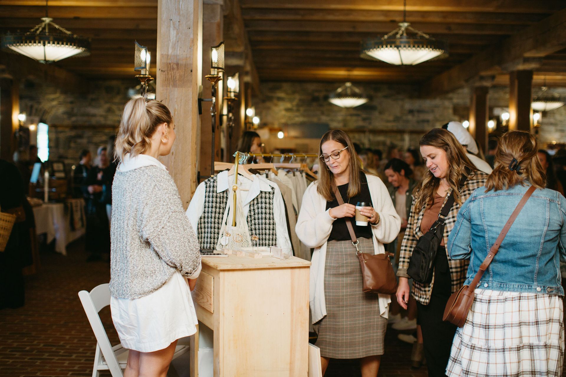 A group of women are standing in a room looking at clothes.