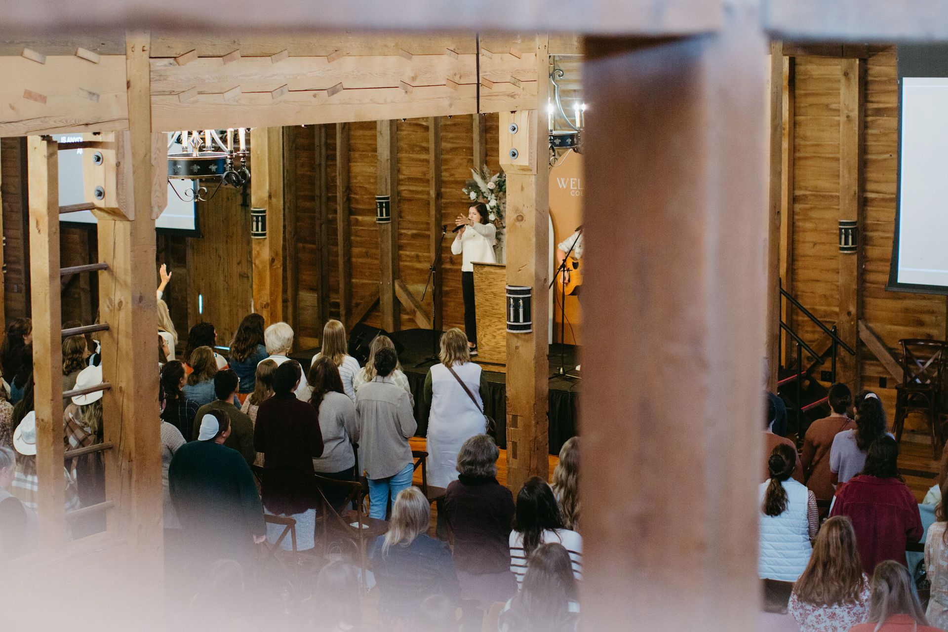 A large group of people are sitting in a wooden room.