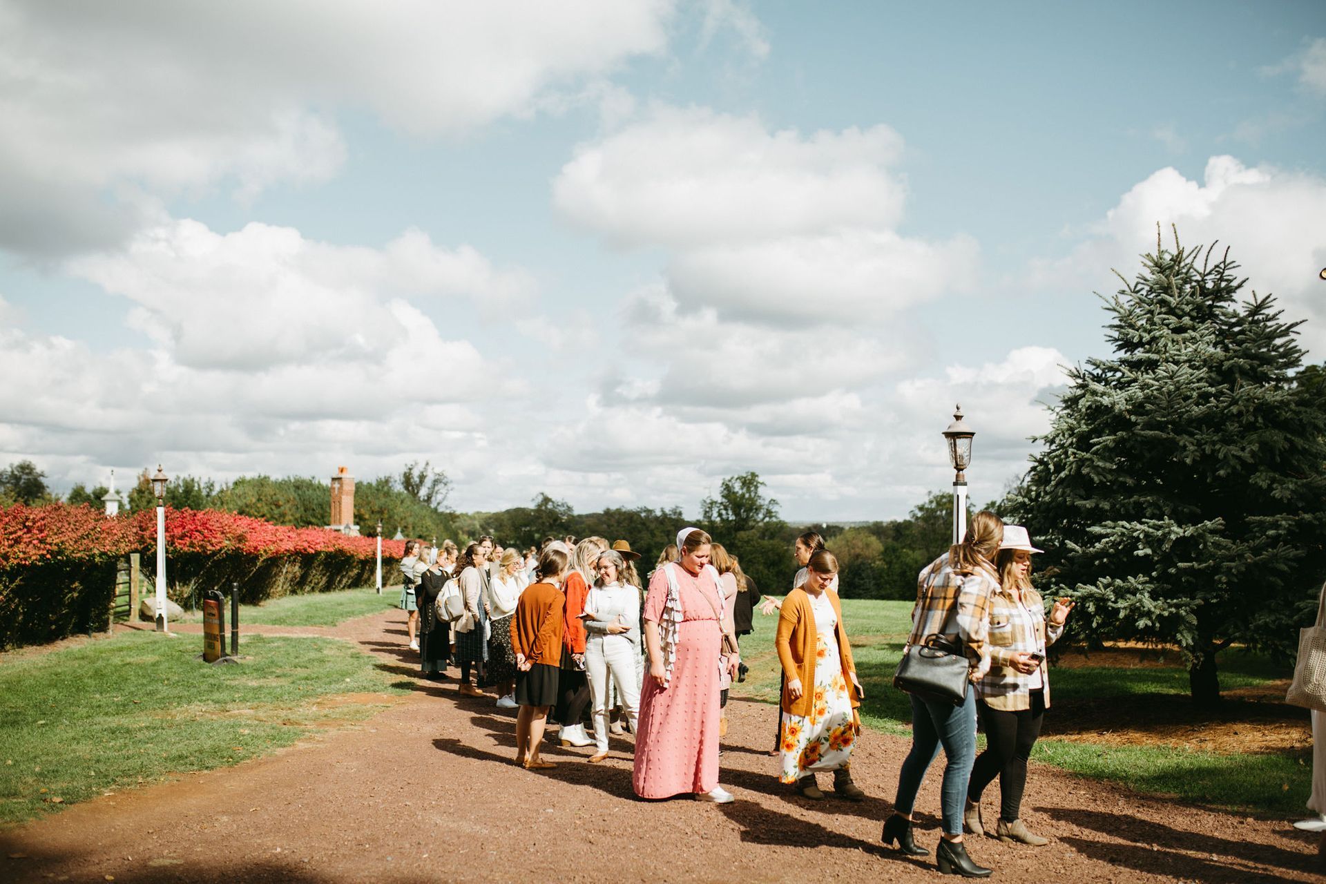 A group of people are walking down a dirt road.
