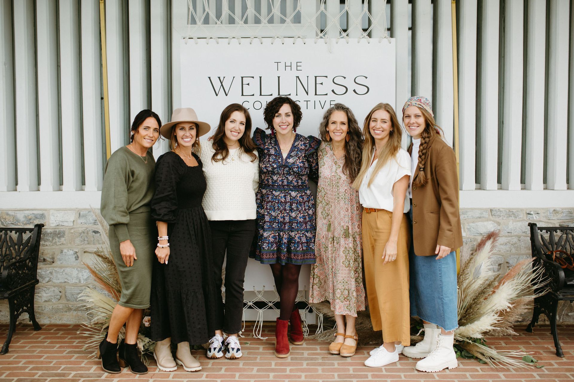 A group of women are posing for a picture in front of a sign that says wellness.