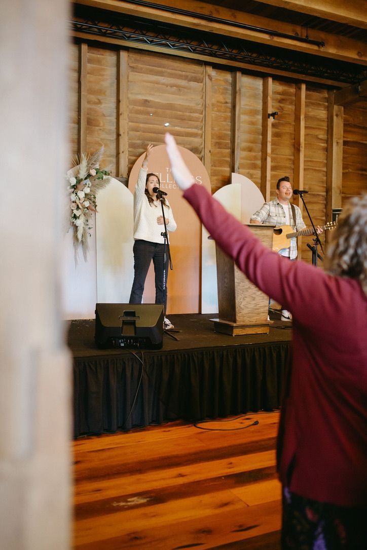 A woman is standing on a stage with her arms outstretched in front of a microphone.