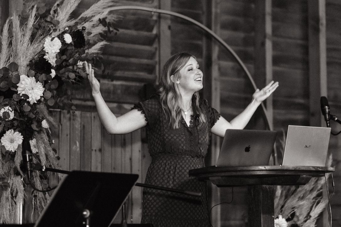 A woman is standing at a podium with her arms outstretched in a black and white photo.