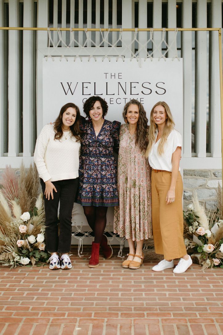 A group of women are posing for a picture in front of a sign.