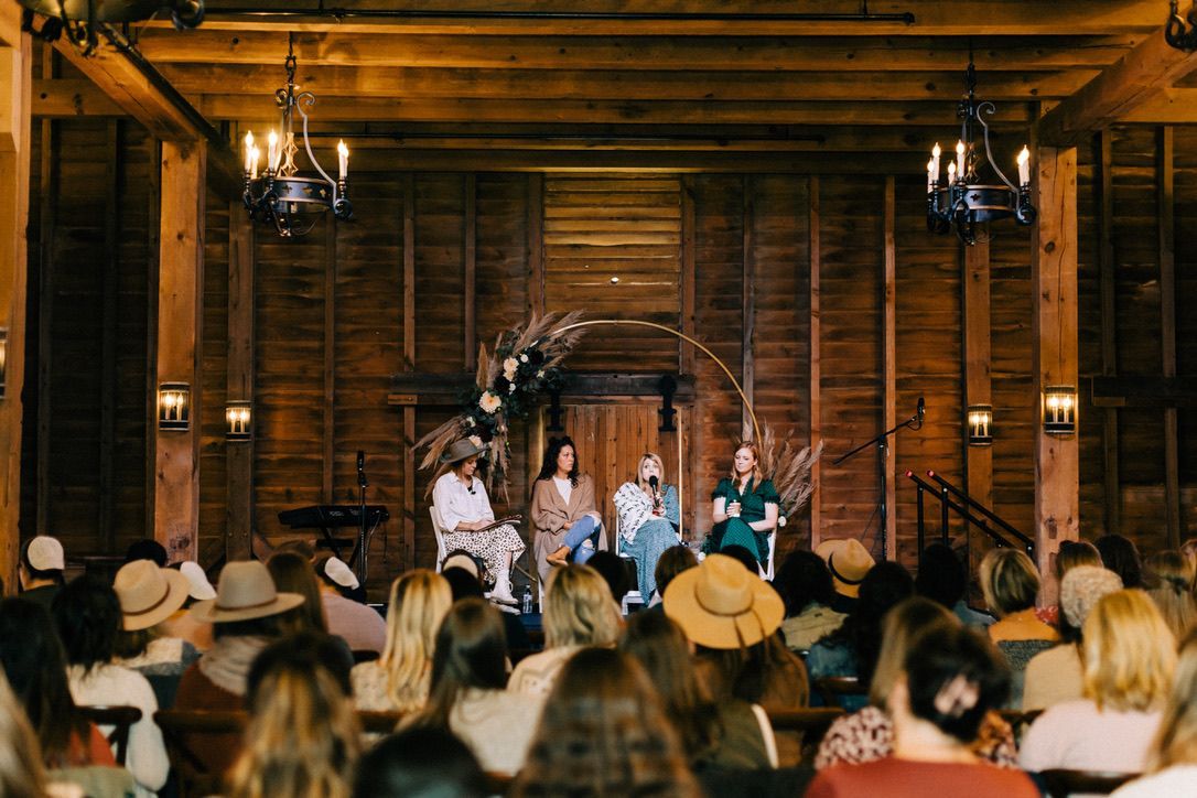 A group of people are sitting in front of a stage in a wooden building.