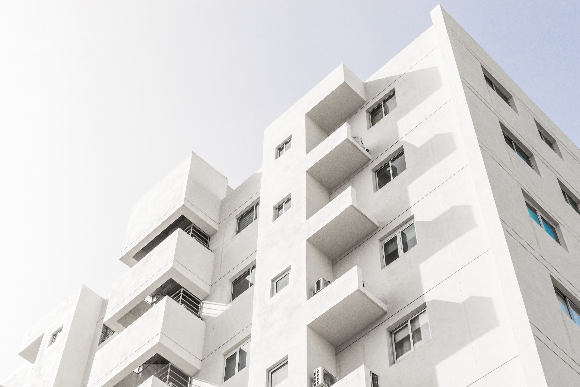 Casa de color azul claro con base de ladrillo marrón, techo verde, entrada para vehículos y césped.