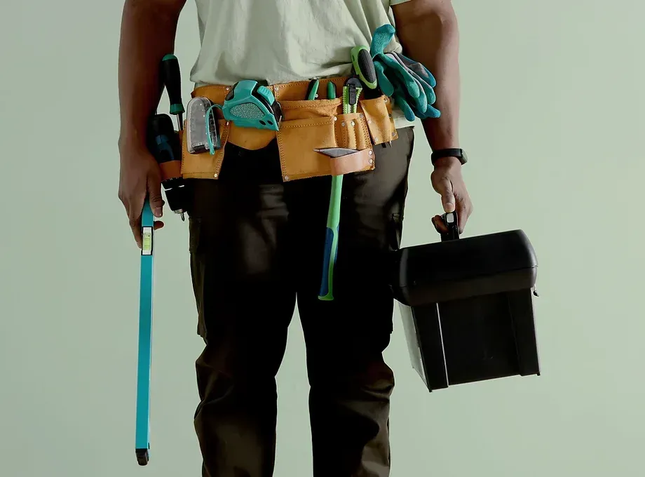 A man is wearing a tool belt and holding a toolbox