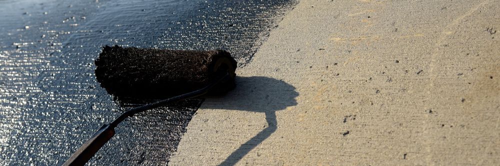 A Paint Roller Applies Black Sealant to a Concrete Surface, Leaving a Wet — 1 Time Waterproofing In East Ballina, NSW