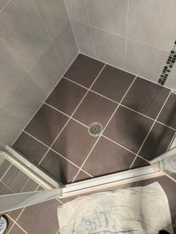 Shower stall with brown floor tiles, gray wall tiles, and a drain— 1 Time Waterproofing in East Ballina, NSW