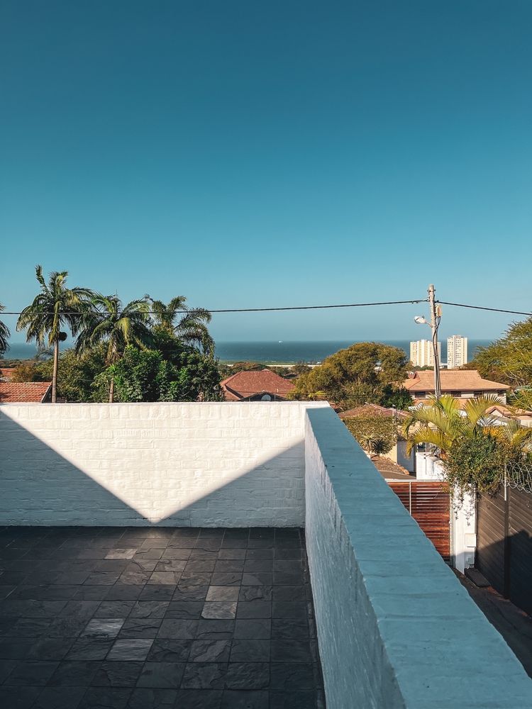 A White Brick Wall on a Rooftop, With a View of Trees, Ocean, and Clear Blue Sky — 1 Time Waterproofing In East Ballina, NSW