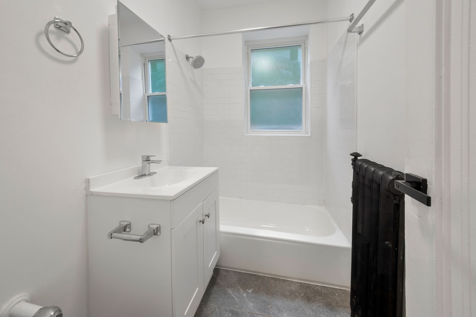White bathroom with sink, cabinet, tub, and towel rack.