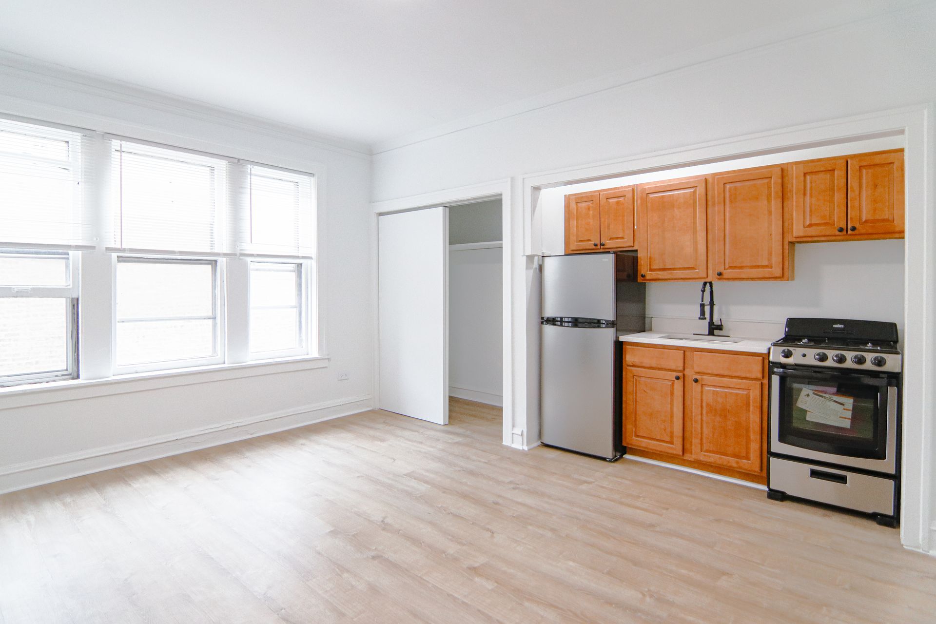 Empty apartment interior with kitchen and large windows.