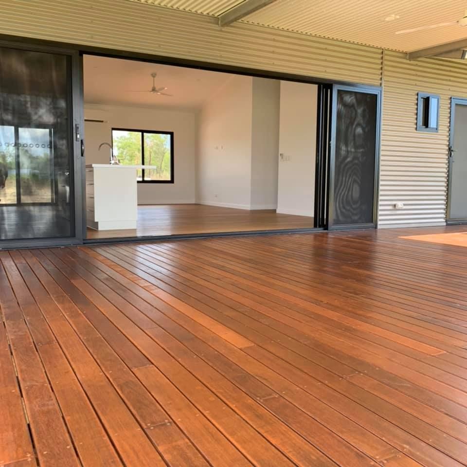 A Large Wooden Deck With A Sliding Glass Door Leading To A Kitchen — SLS Builders Pty Ltd in Humpty Doo, NT