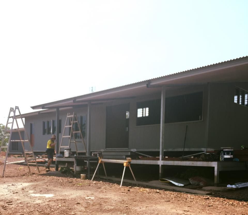 A Man Is Standing On A Ladder In Front Of A House Under Construction in Humpty Doo, NSW