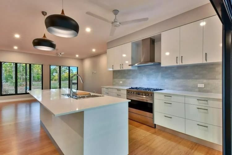 A Kitchen With White Cabinets, a Stove, a Sink and a Ceiling Fan — SLS Builders Pty Ltd in Humpty Doo, NT