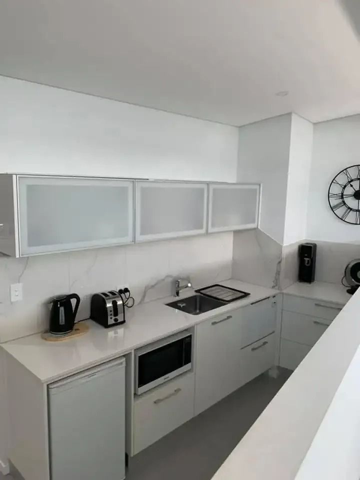 A Kitchen With White Cabinets and a Clock on the Wall — SLS Builders Pty Ltd in Humpty Doo, NT