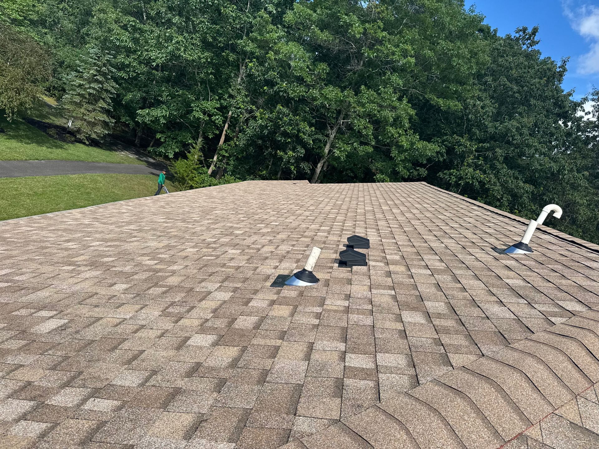 A roof with a lot of shingles on it and trees in the background.