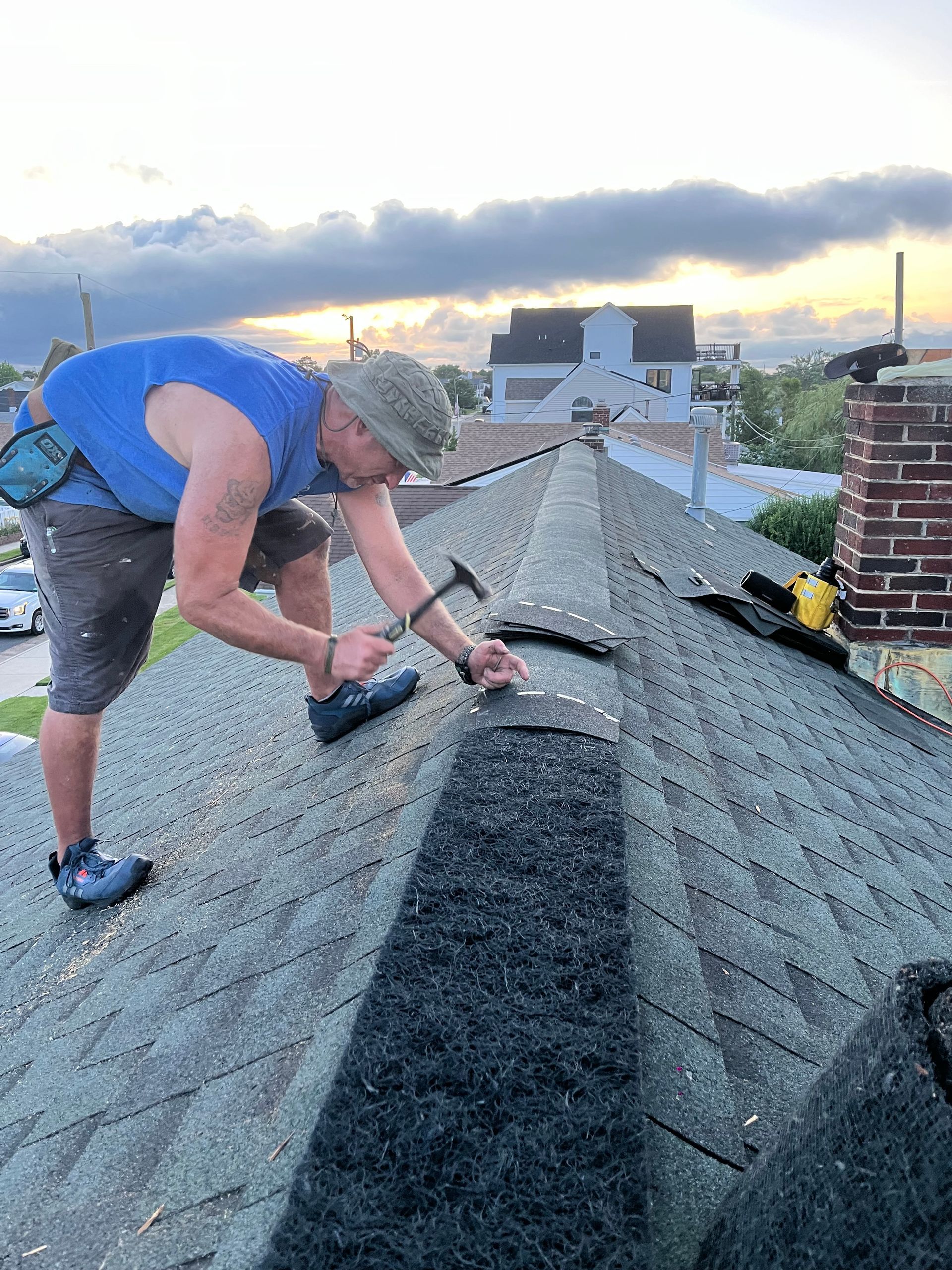 A man is kneeling on a roof with a view of the ocean