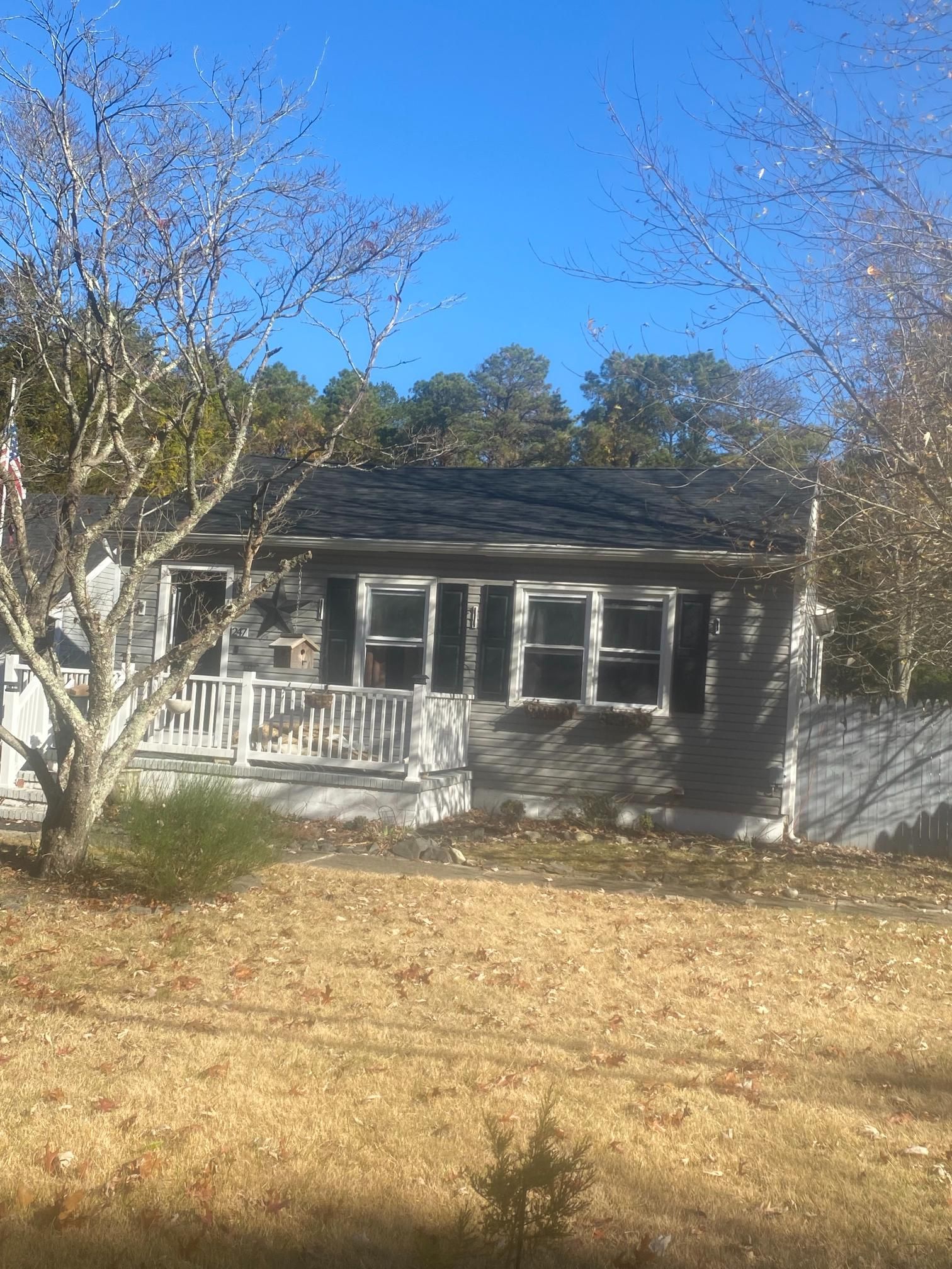 A house with a black roof is sitting in the middle of a field.