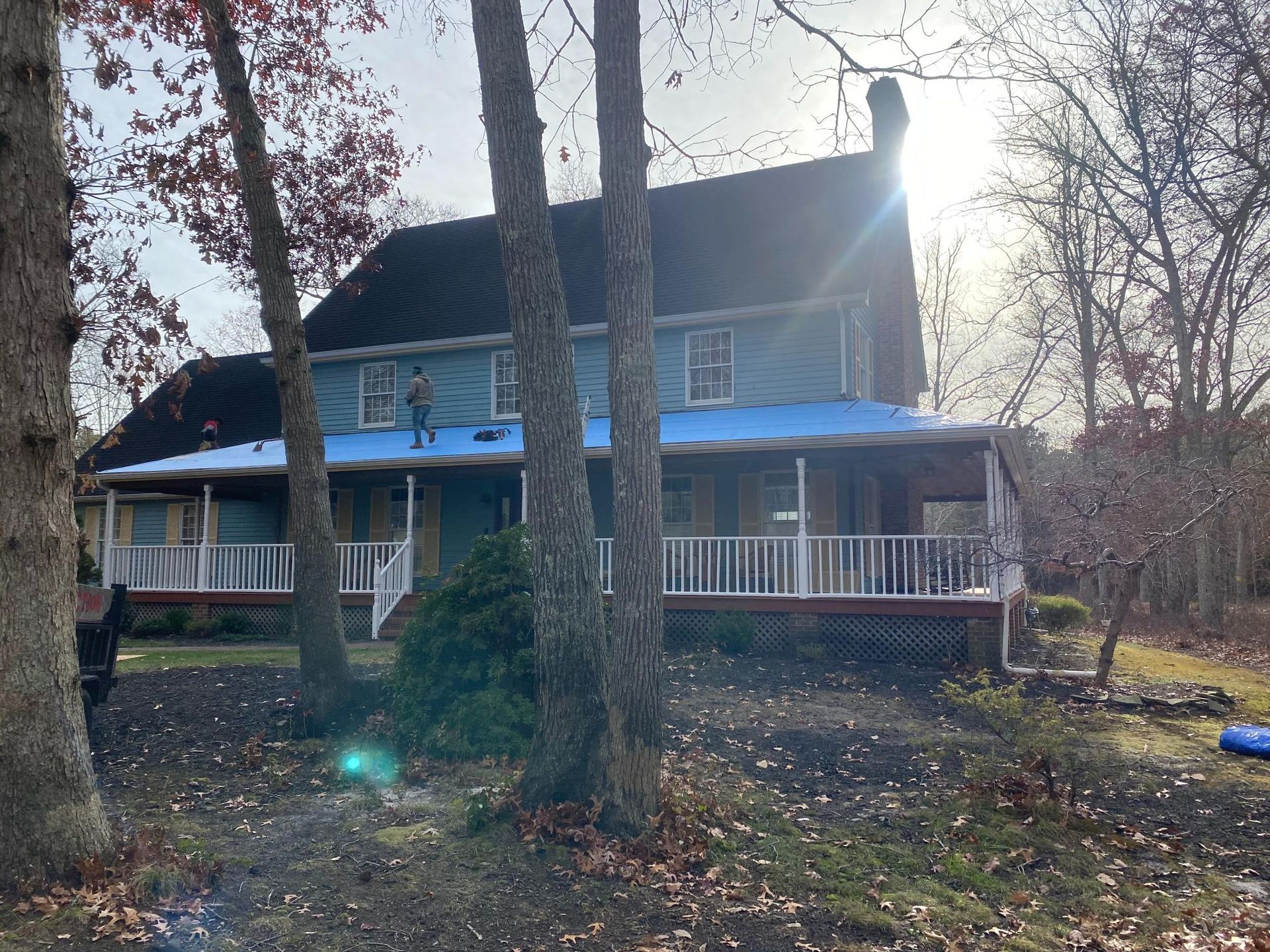 A house with a blue roof is surrounded by trees.