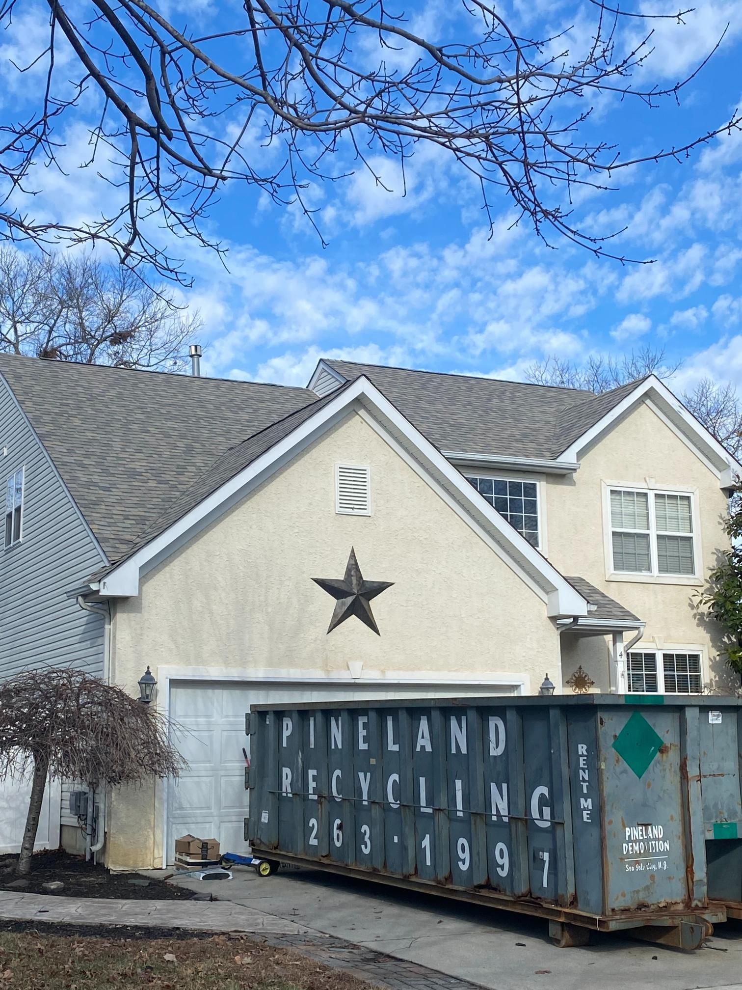 A house with a dumpster in front of it that says pineland recycling