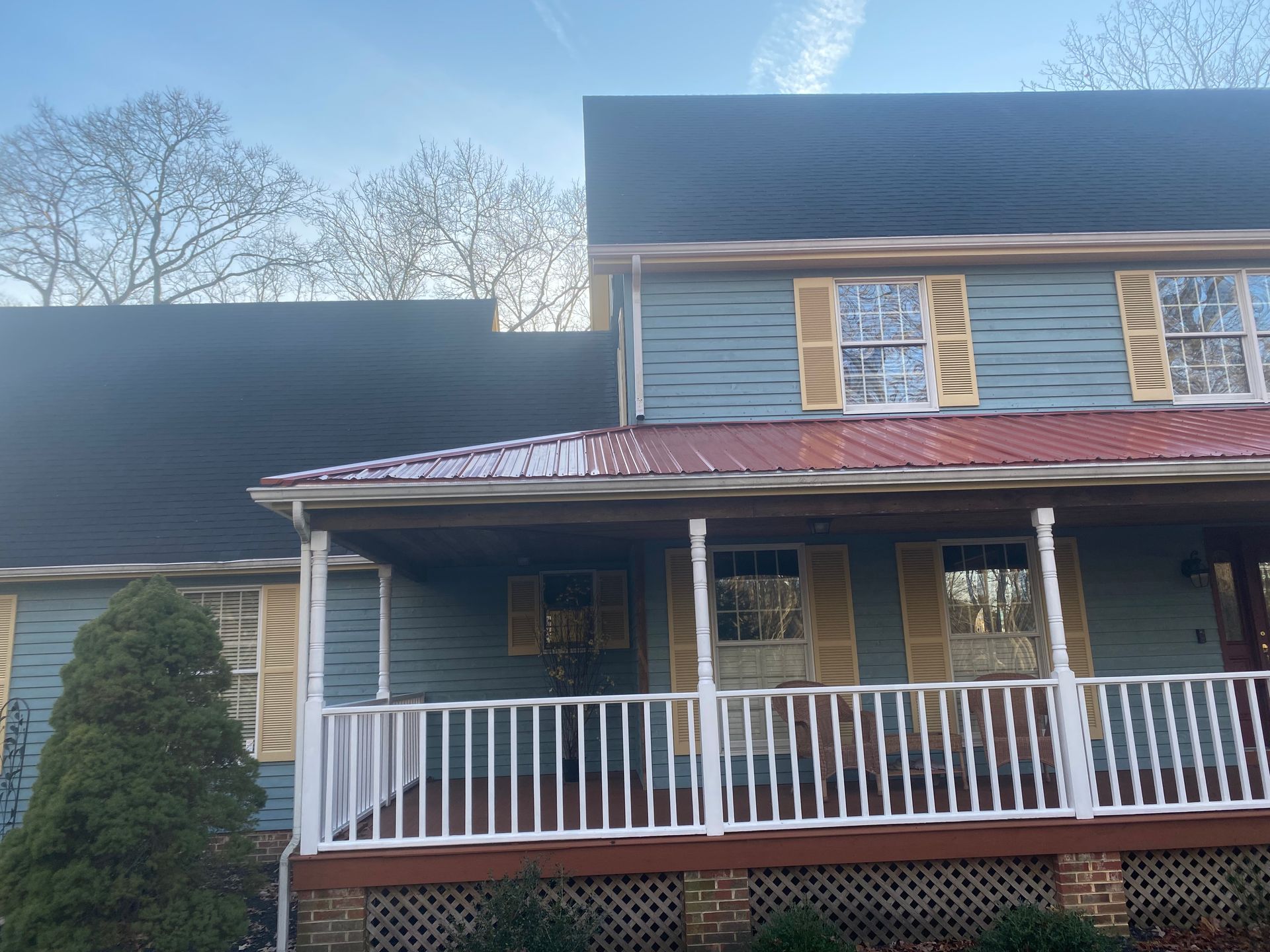 A blue house with a red roof and a porch.