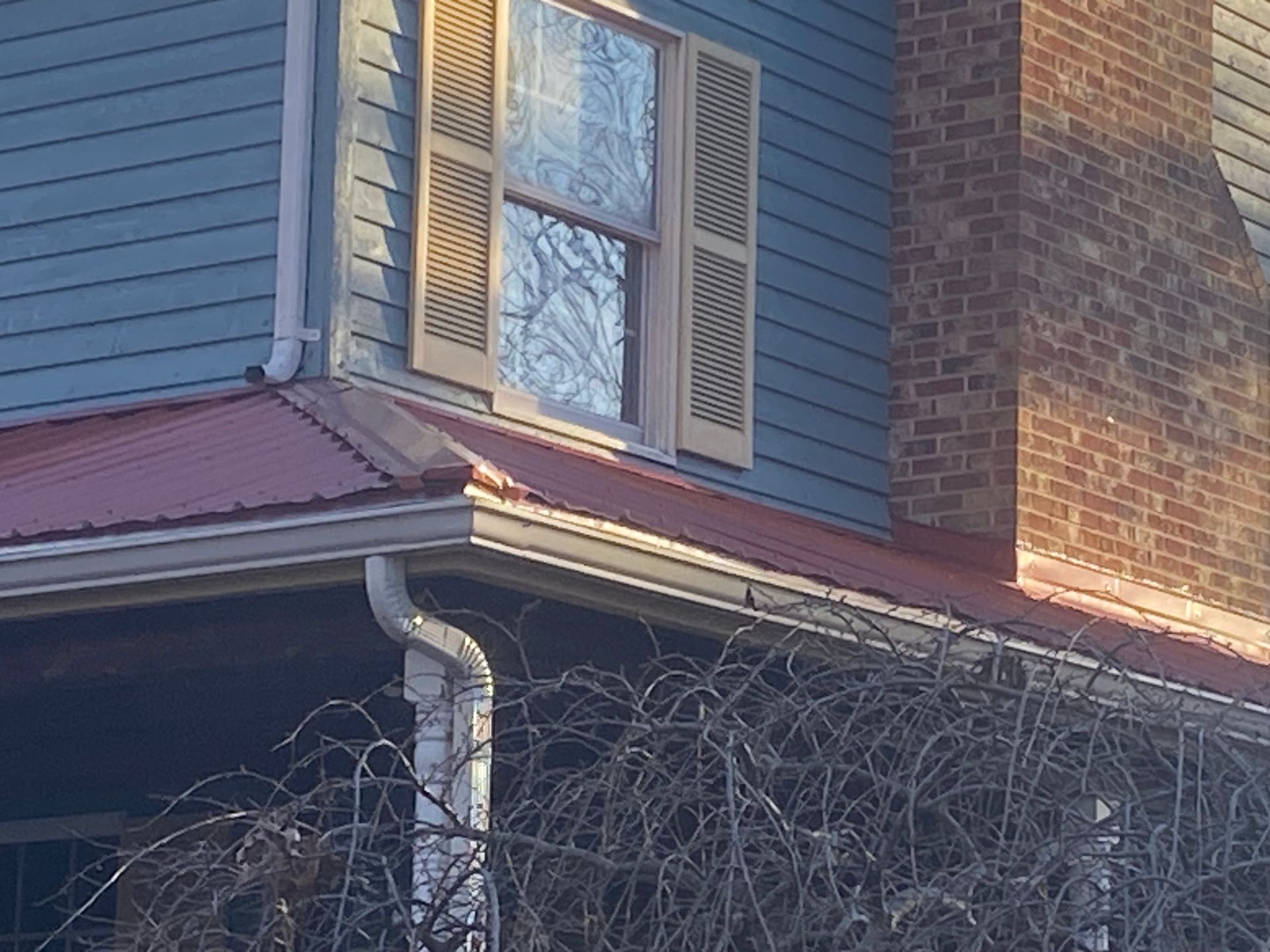A blue house with a red roof and a brick chimney