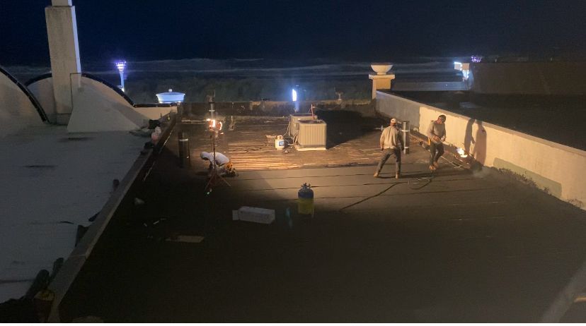 A group of people are standing on top of a roof at night.