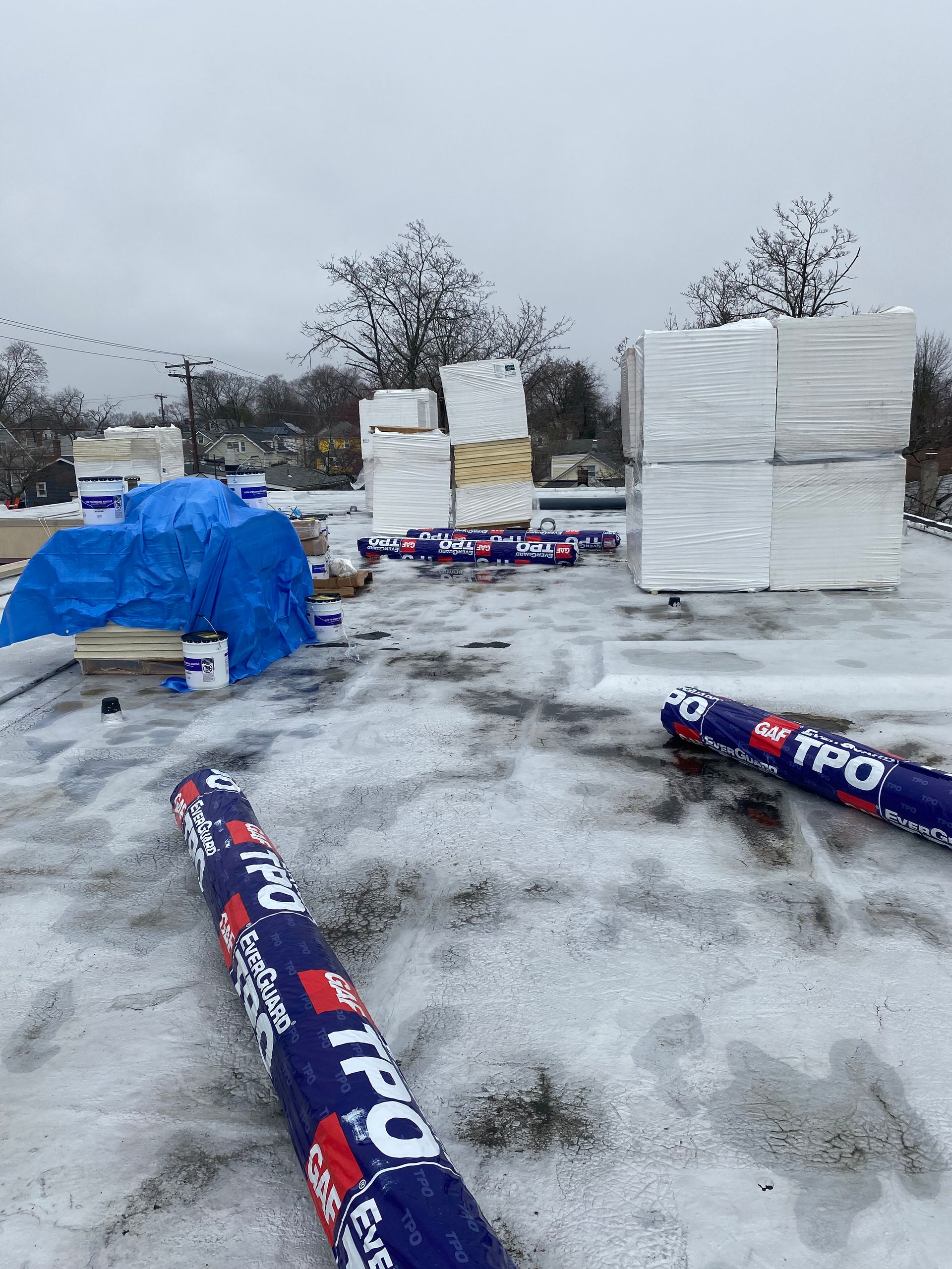 A blue tarp is sitting on top of a snow covered roof.