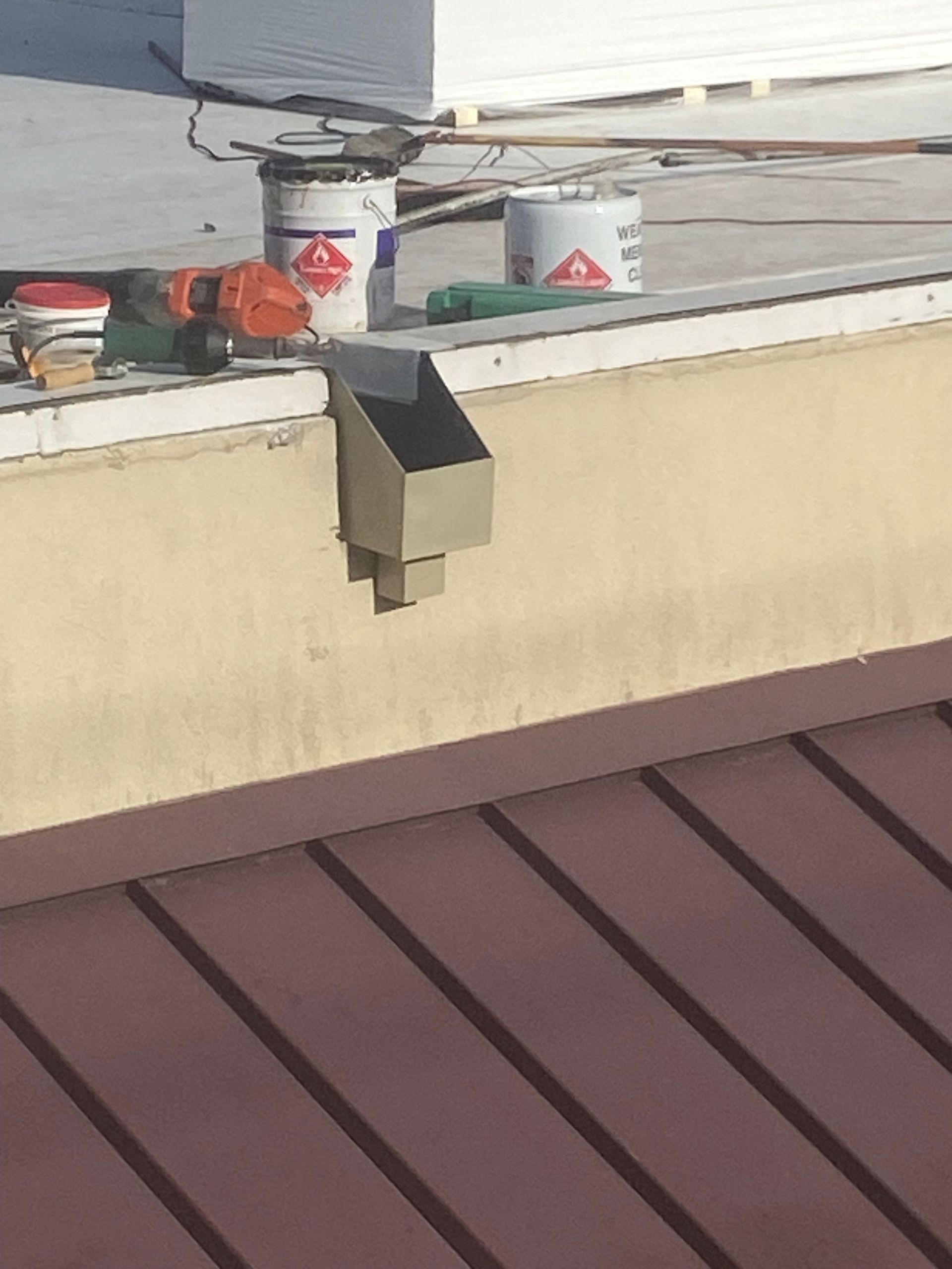 A roof with buckets of paint and tools on it