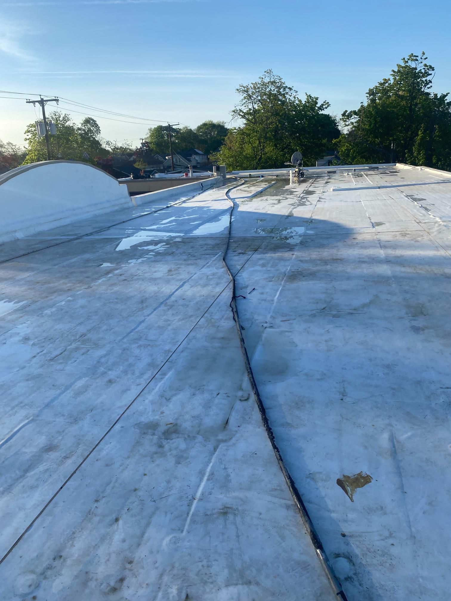 A white roof with a hole in it and trees in the background.