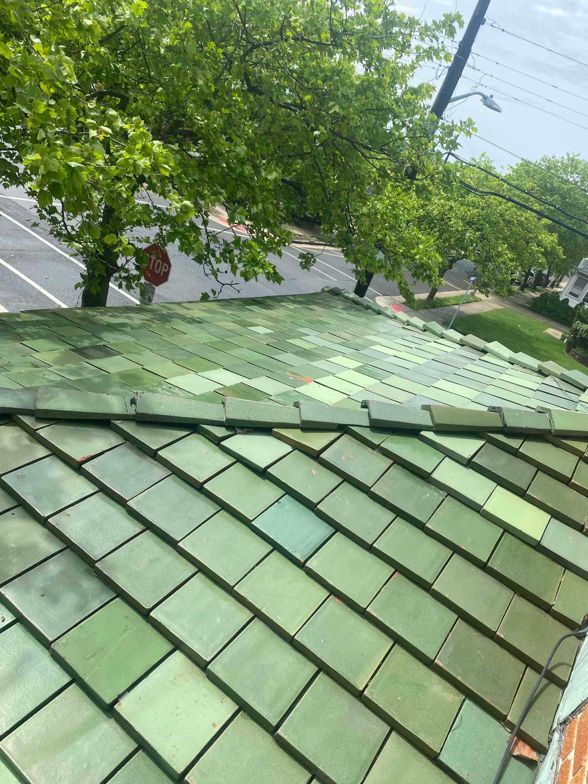 Green tiled roof, top view, with trees and street visible in the background.
