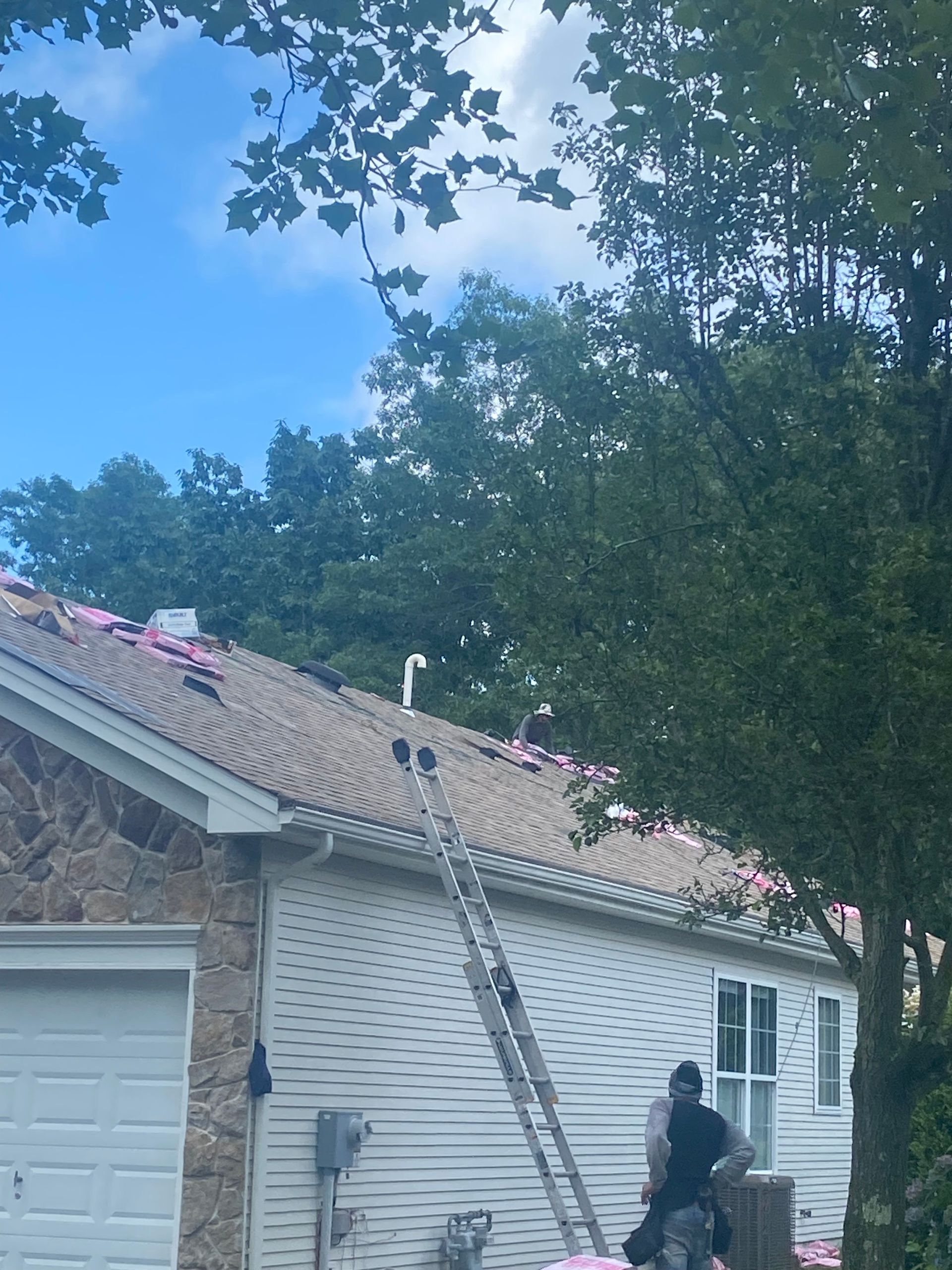 A man on a ladder is working on the roof of a house.