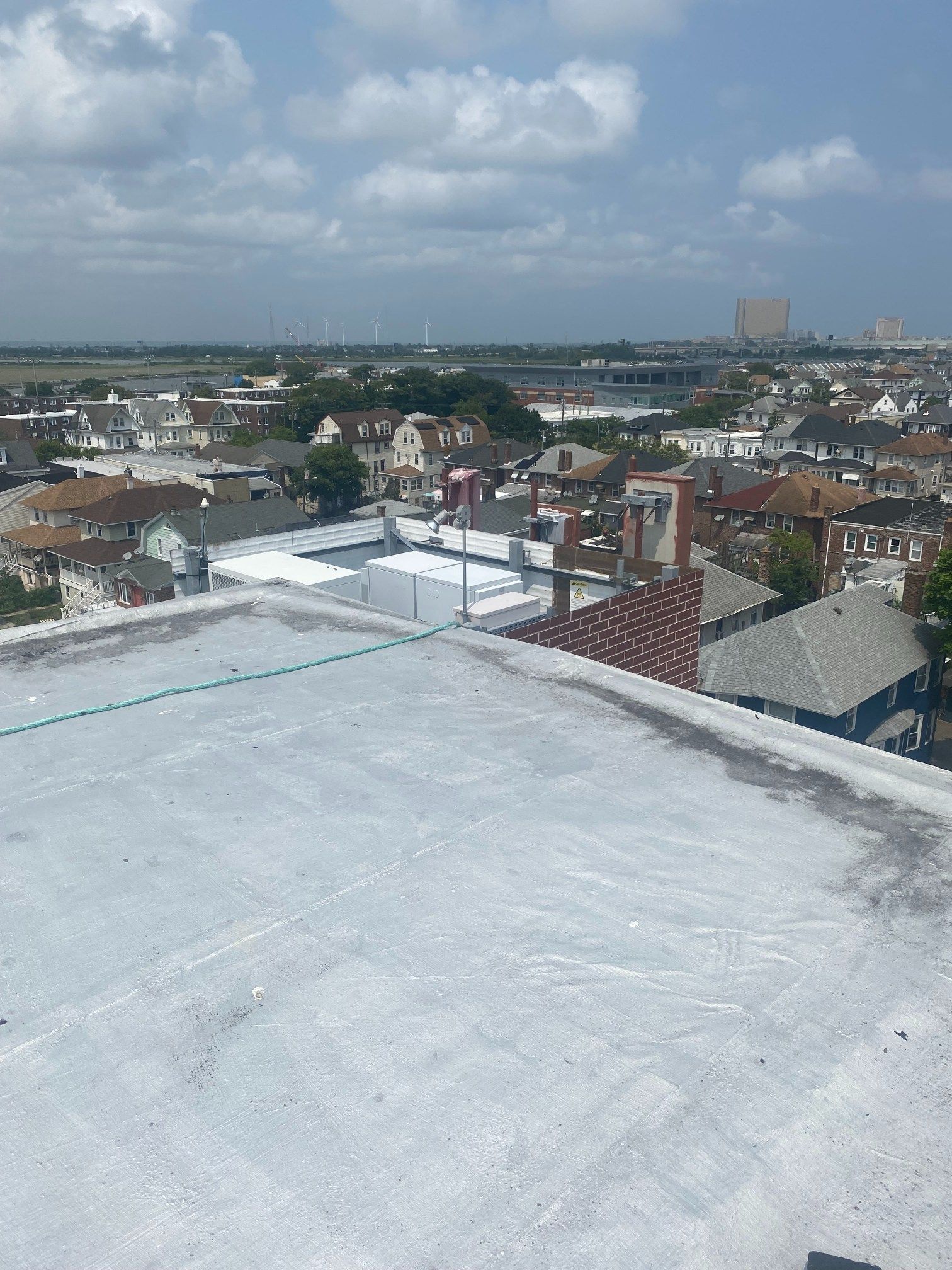 View from a rooftop, houses and distant buildings under a cloudy sky.