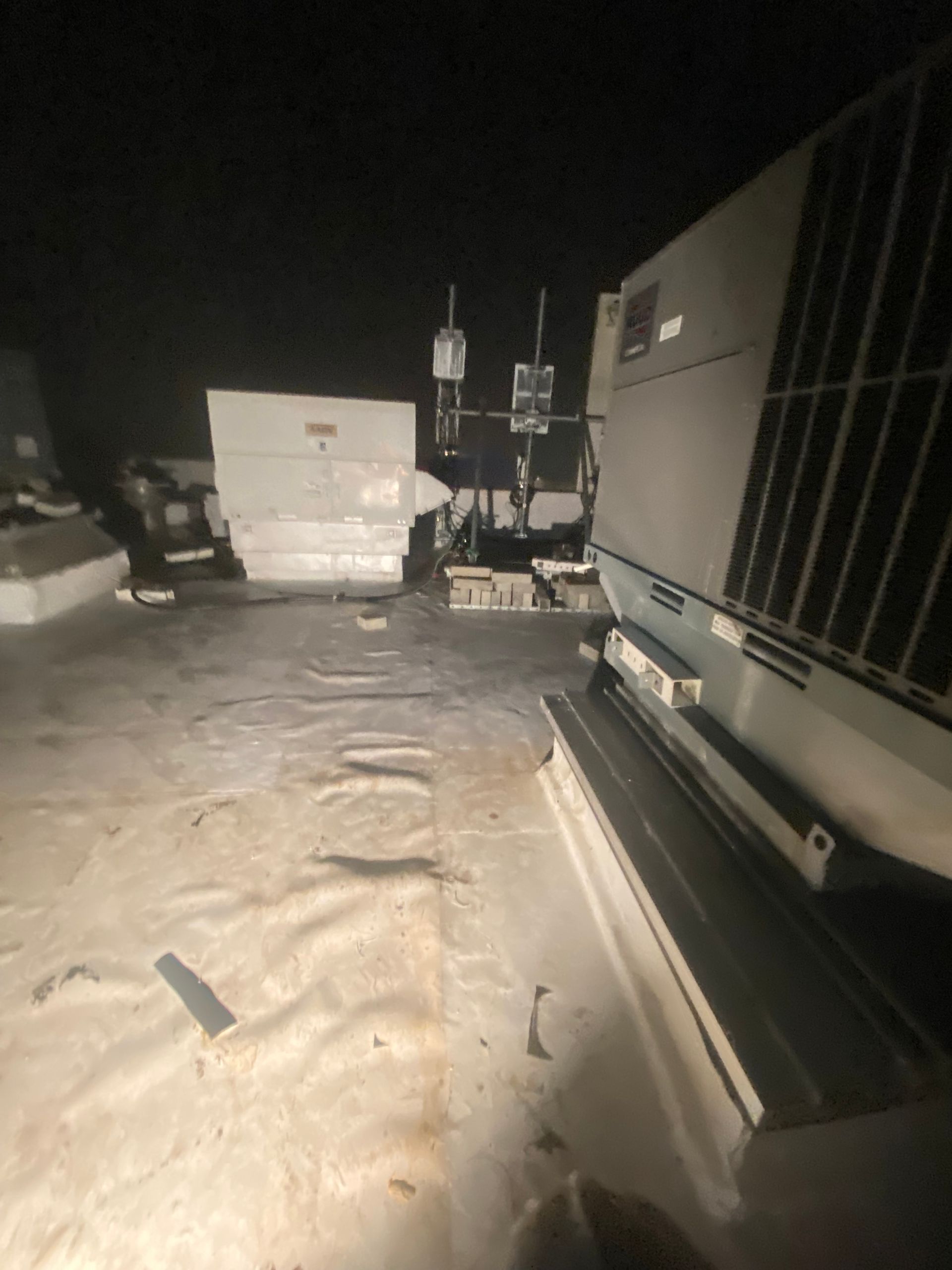 Snow-covered RV parking lot at night with large trailers and a ladder visible.