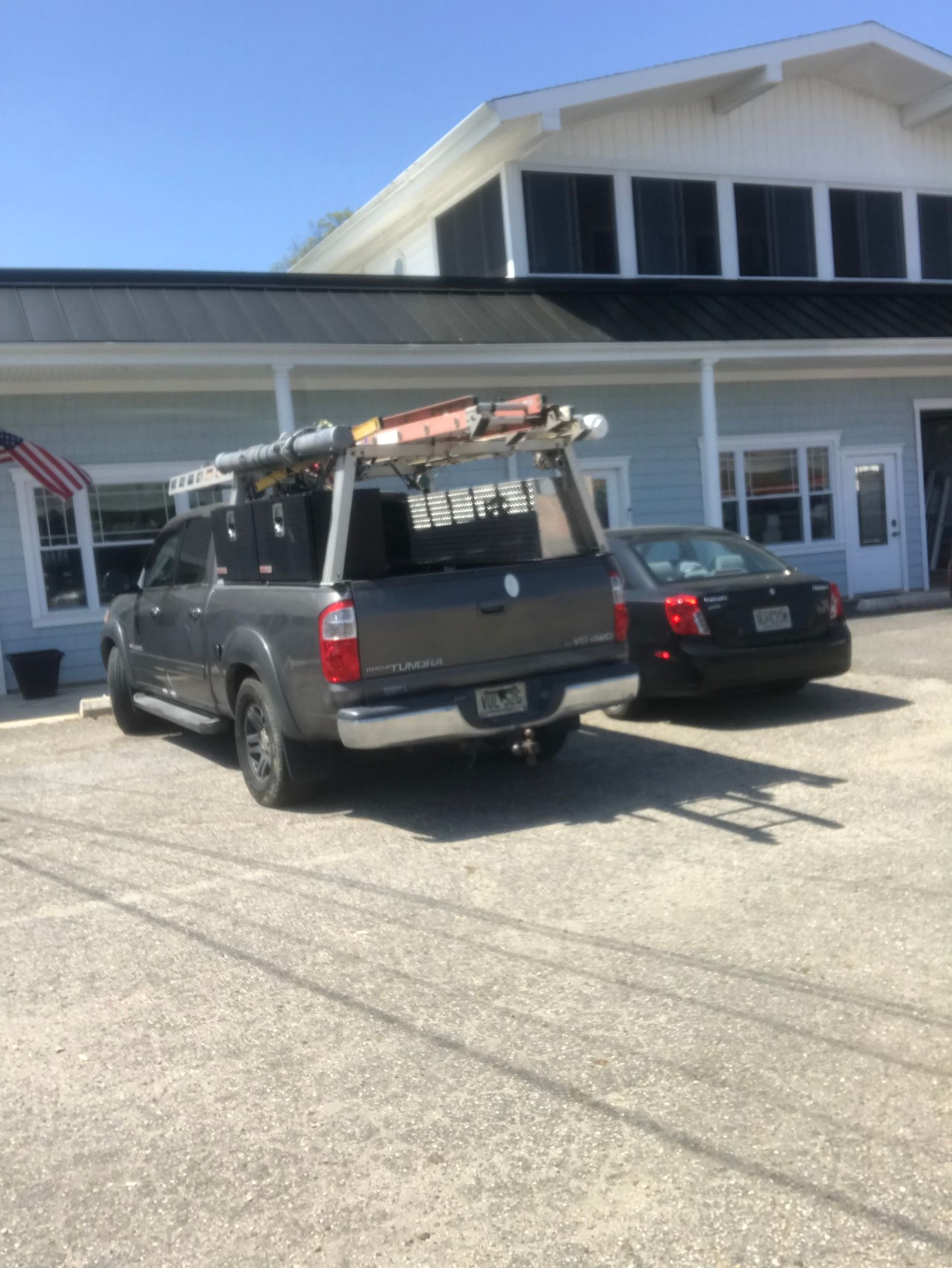 A truck with a ladder on top of it is parked in front of a building.