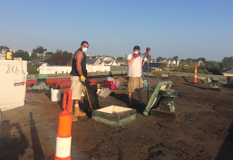 Two men wearing masks are working on a roof.