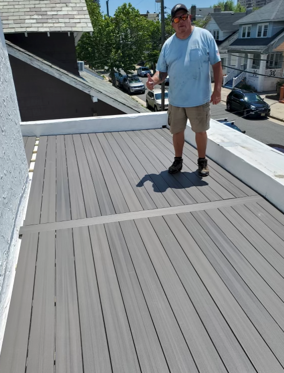 A man in a blue shirt is standing on a deck