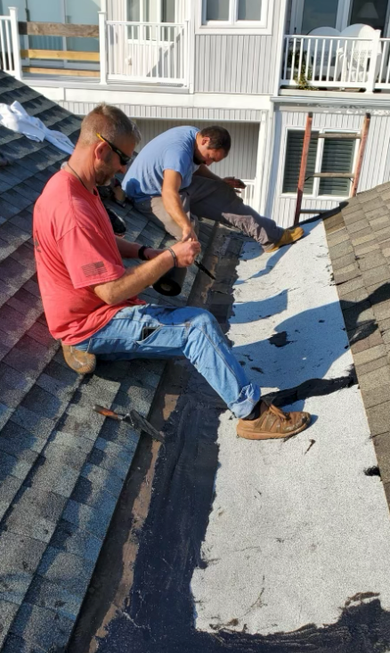 Two men are working on the roof of a house.