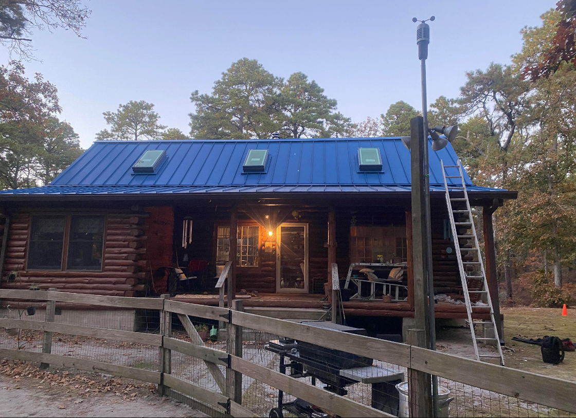 A log cabin with a blue roof is being painted.