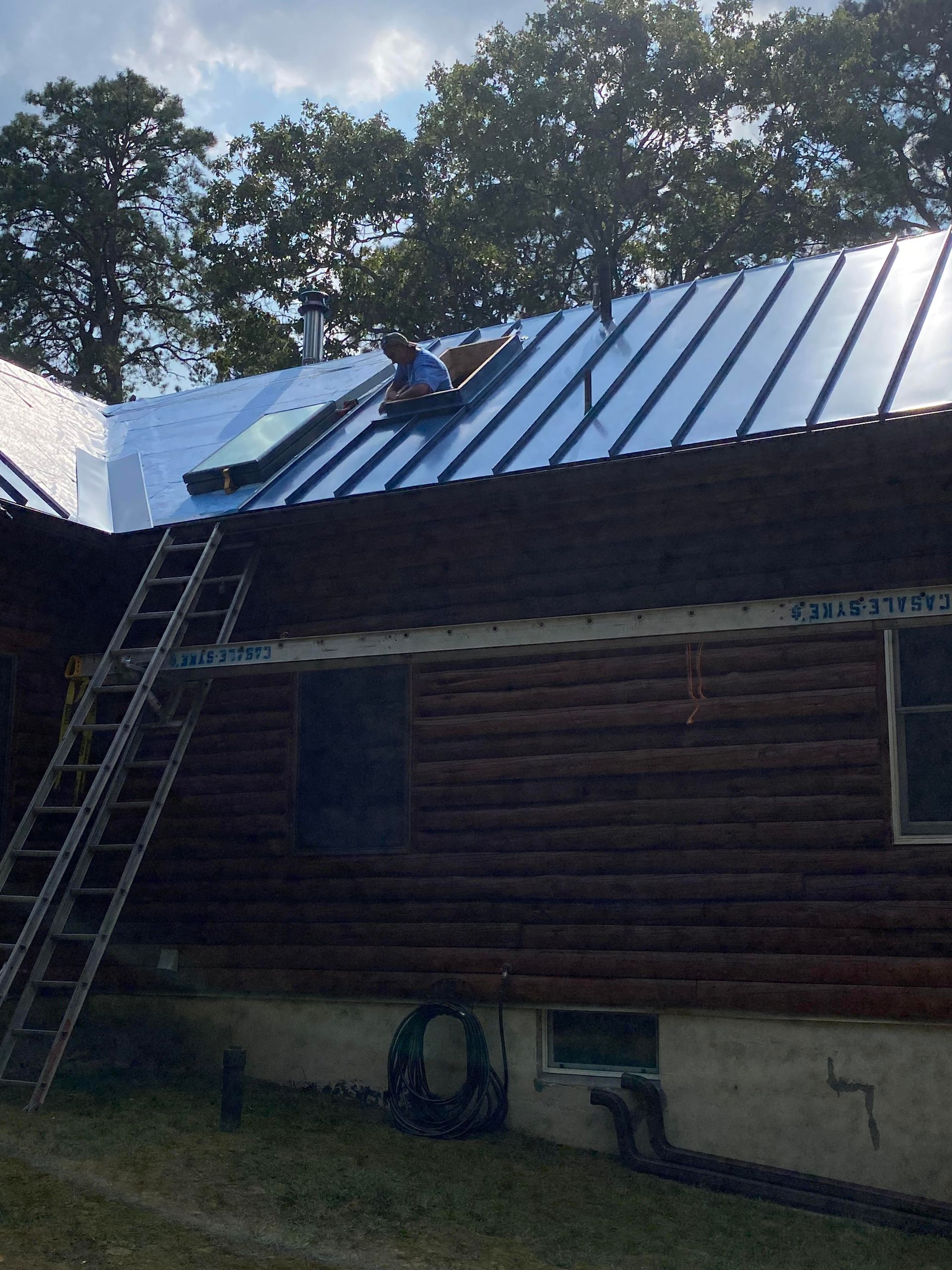 A man is working on the roof of a log cabin
